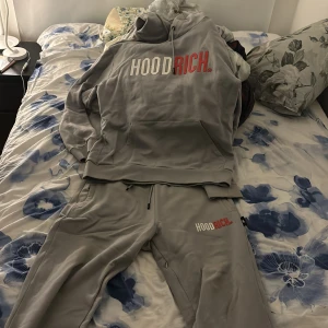 Grå dress från Hoodrich - Säljer ett par grå mjukisbyxor från Hoodrich i mycket bra skick. De har en bekväm passform med resår och snörning i midjan. Perfekta för en avslappnad stil eller träning. Loggan är tryckt i vitt och rött på benet. Supermjuka och sköna att ha på sig!