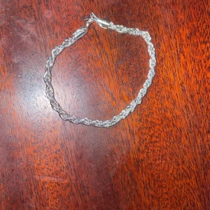 Silverfärgat Cordel  armband - Säljer ett snyggt silverfärgat armband med flätad design. Det är i mycket bra skick och har en klassisk karbinhake för enkel användning. Perfekt för både vardag och fest!