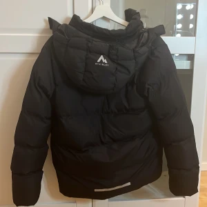 Svart dunjacka från McKinley - Säljer en svart dunjacka från McKinley i storlek 158/164💗. Inga tecken på användning och jackan är perfekt för kalla vinterdagar med sin tjocka vaddering och långa ärmar. Den har en praktisk huva som är avtagbar💞