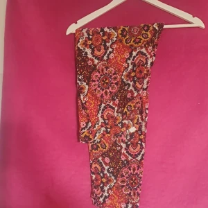 Färgglad mönstrad klänning - Säljer en fin sommar byxa med ett färgglatt mönster. Perfekt för sommardagar eller en festlig kväll. Materialet känns lätt och luftigt, vilket gör den bekväm att bära. 