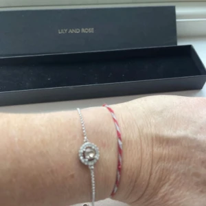 Silverarmband från Lily and Rose - Elegant silverarmband från Lily and Rose med en glittrig detalj i mitten. Perfekt för att lägga till en touch av glamour till din outfit. Armbandet är i mycket bra skick och kommer i originalförpackning.