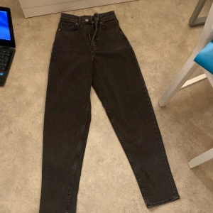 Svarta jeans från H&M Divided - Säljer ett par svarta jeans från H&M Divided i storlek 32. De är högmidjade och har en klassisk femficksdesign med knapp och dragkedja framtill. Perfekta för både vardag och fest! 🖤
