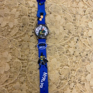 Blå Batman Barn Klocka  - Cool Batman-klocka med blått armband och Batman-motiv. Perfekt för unga superhjältefans! Klockan har en tydlig urtavla med siffror och en färgglad design. Armbandet är dekorerat med Batman-figurer och logotypen. En rolig accessoar för vardagsbruk.    Nya batteri, 3 år +     115kr/st 