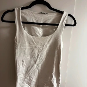 Vit linnetopp - Säljer en enkel och stilren vit linnetopp. Perfekt för sommardagar eller som ett basplagg i garderoben. Toppen är ärmlös och har en rund halsringning. Passar till både jeans och kjol för en avslappnad look.