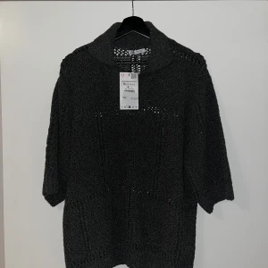 Grå stickad tröja från Zara - Säljer en snygg grå stickad tröja från Zara i storlek M. Tröjan har ett unikt mönster med små hål och är perfekt för höst och vinter. Den har trekvartsärmar och en bekväm passform. Perfekt för att hålla sig varm och stilren! 🖤 Nyskick med taggen kvar.