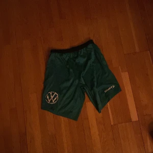 Gröna träningsshorts från Craft - Säljer ett par gröna träningsshorts från Craft i storlek herr XS. De har en elastisk midja och är perfekta för träning. Shortsen har en volkswagen på ena benet och är i mycket bra skick. Perfekta för sommarens träningspass! säljer två för 150 en för 100