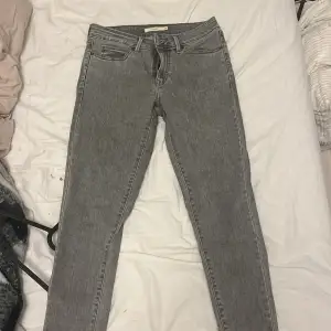 Säljer ett par grå Levis 711 Skinny jeans i bra skick. De är tighta och har en klassisk femficksdesign med dragkedja och knapp. Perfekta för både vardag och fest! 🖤