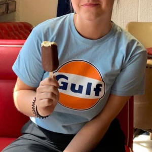 Retro ljusblå t-shirt med Gulf-tryck  - Säljer en ljusblå t-shirt i storlek S. Den har ett stort, retro Gulf-tryck i orange och blått på framsidan. 