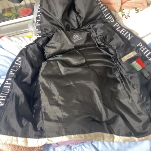 Smuts vit väst från Philipp Plein - Säljer en snygg smuts vit väst från Philipp Plein. Den är quiltad och har en cool huva med märkesnamnet tryckt på insidan. Västen har dragkedja fram och två fickor med dragkedjor. Perfekt för höst och vår när du vill ha något stilrent och bekvämt.