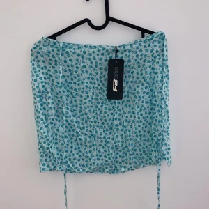 Blommig kjol från FB Sister - Söt blommig kjol från FB Sister i ljusblått med små blommor i mörkare blå nyanser. Kjolen har en luftig och lätt design, perfekt för varma sommardagar. Den har knytband på sidorna för en justerbar passform. Perfekt för en avslappnad sommarlook! 🌸