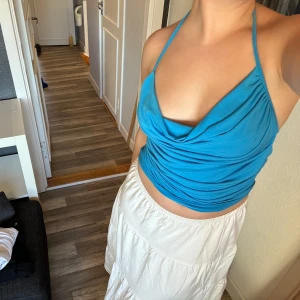 Blå halterneck topp från NA-KD - Snygg blå halterneck topp från NA-KD i mjukt material. Perfekt för sommaren eller en kväll ute🙏🏼Toppen har också en draperad design som ger en cool look. Passar bra till både kjol och jeans!🩵 Bara använd nån gång🤍