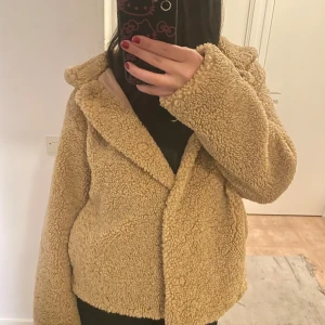 Beige teddyjacka med huva - Mysig beige teddyjacka med huva. Jackan har en mjuk och fluffig yta med knappar framtill. Insidan är fodrad med ett slätt material. Passar perfekt till höst och vinter. 🧥✨den är i oanvänd skick, används 2-3 ggr och är köpt i Belgien på affär, Ming Casual. Storlek L men ser ut som S/M !! 