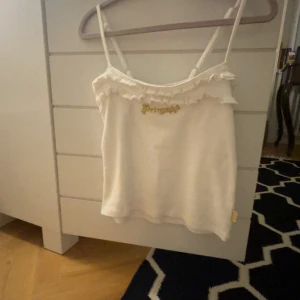 Vit linne med volangdetaljer - Säljer en söt vit linne med smala axelband och volangdetaljer. Toppen har gullig text där det står ”princess”. Från Disney. Står ingen strl men gissar på xs.