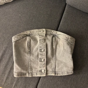Grå jeans tubtopp från H&M - Säljer en snygg grå jeans tubtopp från H&M i storlek XS. Den är använd fåtal gånger då den har varit för trång för mig (den har ingen stretch) så säljer den så den istället kommer till användning🩷