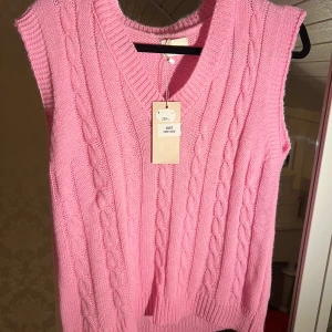 Rosa stickad väst - Säljer en superfin rosa stickad väst med flätmönster och v-ringning. Perfekt för lager-på-lager under hösten eller våren. Västen är i nytt skick och passar de flesta tack vare one size-storleken. Ett måste för garderoben! 💖