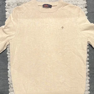 Morris tröja beige  - Säljer en stilren beige tröja från Morris i storlek M. Tröjan är i mycket bra skick och har en diskret broderad logga på bröstet. Perfekt för både vardag och festliga tillfällen. Den är tillverkad i ett mjukt material som känns skönt mot huden.