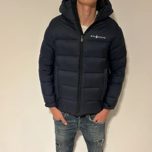  Sail Racing jacka - Säljer en snygg mörkblå pufferjacka från Sail Racing. Jackan är i extremt bra skick och är knappt använd. Storleken är S men passar XS. Nypris 4000, säljes för 1500