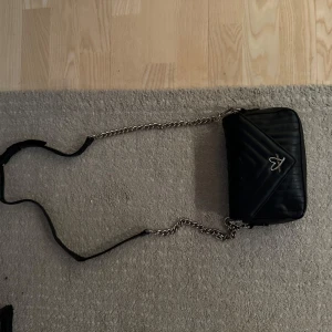  axelväska med kedja Victoria secret - Snygg svart axelväska i quiltat mönster med en cool kedja som axelrem. Väskan har en dragkedja och en söt rosa hjärtdetalj på framsidan. Perfekt för både vardag och fest!