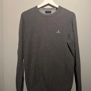 Grå GANT tröja  - Säljer en stilren grå tröja från GANT i mycket bra skick. Den är långärmad och har en diskret logga på bröstet. Perfekt för alla årstider, och funkar lika bra till vardags som till lite finare tillfällen. Tröjan är mjuk och bekväm, ett måste i garderoben! Öppen för byten.