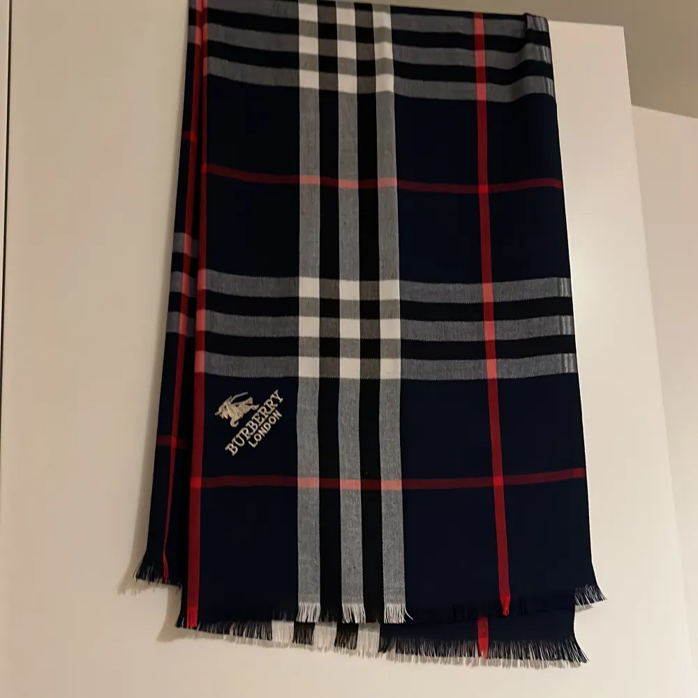 Säljer en snygg rutig halsduk från Burberry i marinblått med röda och vita detaljer. ( inte äkta ) . Övrigt.