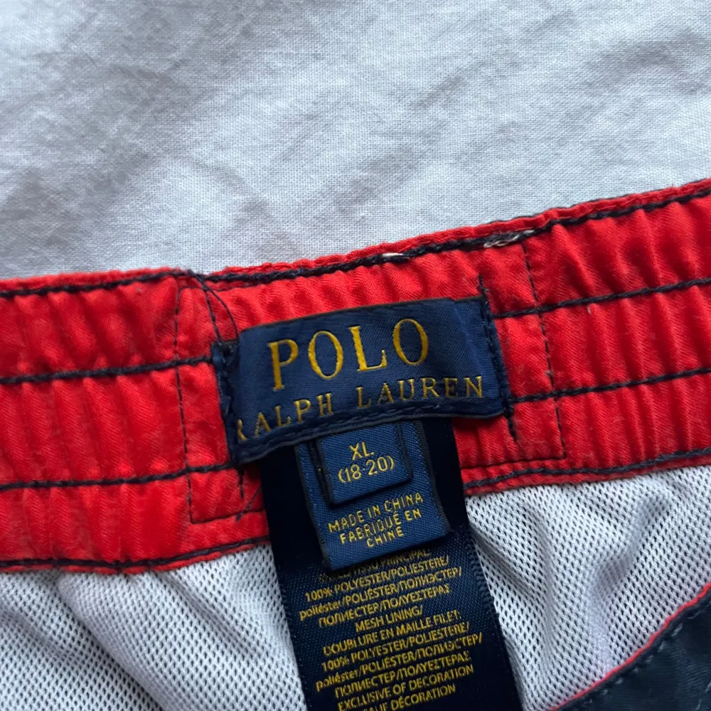 Säljer ett par snygga svarta shorts från Polo Ralph Lauren i storlek XL. De har en röd snörning och ett stort rött logotryck på benet. Perfekta för sommaren med en bekväm passform och elastisk midja. . Shorts.