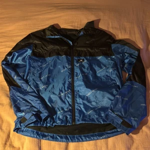 Blå och svart vindjacka från Sweet SKTBS i storlek s - Säljer en blå svart vindjacka från Sweet SKTBS i bra skick. Jackan har ett coolt mönster med märkesloggan över hela tyget, logga på bröstet och en dragkedja framtill. På ryggen över högra axeln är loggan broderad i vitt. Den är även justerbar/dragsko i nedre kant. Kardborre knäppe i ärmslut Hör av dig vid intresse!💯