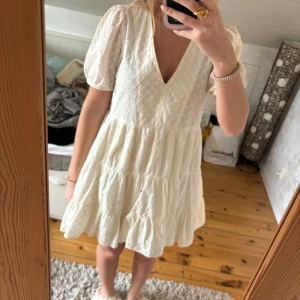 Vit klänning med puffärmar - Perfekt studentklänning från zara, hålbroderi med blommor, v-ringad med korta ärmar. Bra skick.