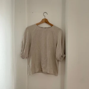Beige blus från NLY Trend - Säljer en stilren beige blus från NLY Trend i storlek 34. Blusen har trekvartsärmar med en lätt puffig design och en diskret dragkedja i ryggen. Perfekt för både vardag och festliga tillfällen. 🥰