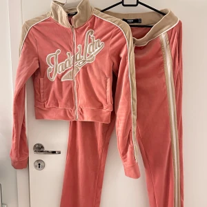 Rosa velourträningsset från Jaded London - Säljer ett supermysigt rosa velourträningsset från Jaded London. Jackan har dragkedja och broderad text på bröstet. Byxorna har en bekväm resår i midjan. Perfekt för en avslappnad dag eller en stilren look på stan. 🩷