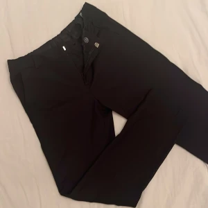 Svarta kostymbyxor från H&M - Säljer ett par stilrena svarta kostymbyxor från H&M i storlek 146. Byxorna har knapp och dragkedja framtill. Hällor för bälte men även elastisk dragsko på insidan för justering av midjan. De är endast använda en gång och  i mycket bra skick. 