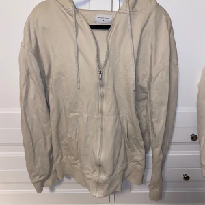 Beige hoodie från Studio Total - Säljer en snygg beige hoodie från Studio Total i storlek M. Den har en dragkedja framtill och en skön luva med snören. Perfekt för en avslappnad stil och passar till alla tillfällen. Hör av dig vid intresse!