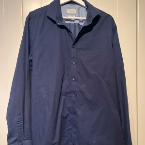Blå skjorta från Bruun & Stengade - Snygg blå skjorta från Bruun & Stengade i slim fit. Skjortan har ett diskret prickigt mönster och knappar framtill. Skjortan är i mycket bra skick, nypris 900:-