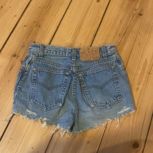 Blå jeansshorts med slitna detaljer - Säljer ett par snygga blå jeansshorts från Levi's i bra skick. De har en cool, sliten look med fransiga kanter och är perfekt för sommaren. Står ingen storlek på dem, men skulle säga dem passar en XXS/XS. 