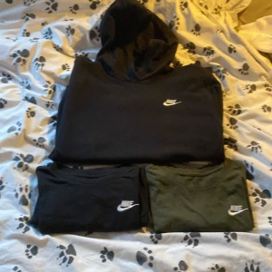 Svart Nike hoodie och två Nike t-shirts i storlek:158    - Säljer en svart hoodie och två t-shirts från Nike. Hoodien är perfekt för höst och vår medan t-shirtsen i svart och grönt funkar året runt. Alla plagg har den klassiska Nike-loggan broderad på bröstet. Dom är använda fåtal gånger och är i mycket bra skick! 