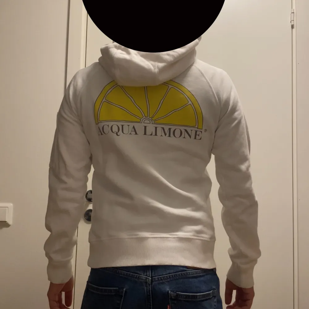 Säljer en snygg vit hoodie från Acqua Limone. Den har en stor gul logga på ryggen och en praktisk ficka med dragkedja på ärmen. Perfekt för både vardag och chill. Passar bra till jeans eller träningsbyxor. Hör av dig vid intresse!. Hoodies.