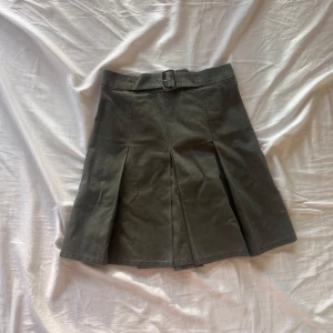 Militärgrön kjol från Aspesi - Säljer en snygg militärgrön kjol från Aspesi i storlek 40. Passar dock mig som vanligtvis har S/36. Kjolen har en stilren design med veck framtill och ett bälte i midjan för extra stilpoäng. Perfekt för både vardag och fest! 🫶