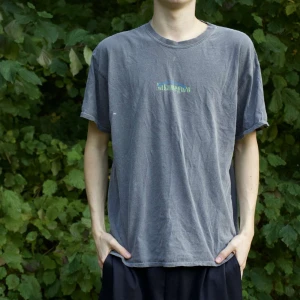 Grå t-shirt med tryck - Säljer en grå t-shirt med coolt tryck på både fram- och baksidan. Den har en avslappnad passform och är perfekt för vardagsbruk. Materialet känns mjukt och bekvämt, perfekt för sommardagar eller som ett lager under en hoodie. Passar bra till jeans eller shorts!