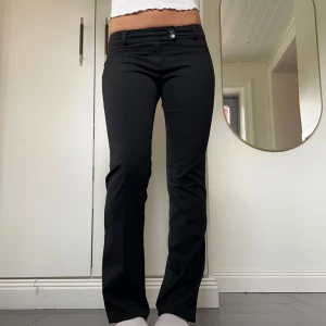 Svarta lågmidjade kostymbyxor - Svarta lågmidjade kostymbyxor med bootcut från Vero Moda i storlek 36. Fint skick. Tvärs över midjan är det 37 cm+ lite stretch och innerbenslängden är ca 80 cm. Jag är 172 för referens! Använd gärna köp nu!