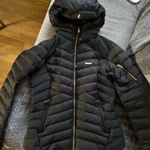 Skidjacka / dunjacka från Peak Performance Stl.M - Säljer en svart Skidjacka/ dunjacka från Peak Performance i storlek M. Jackan är i nyskick, endast använd vid 2 tillfällen. The Montano Jacket from Peak Performance is a stylish ski jacket for women. - Wind and waterproof, Water-repellent coating,Ski pass pocket with zip fastening in the sleeve, Cuffs adjustable with Velcro, Pre-shaped sleeves for extra freedom of movement, Fixed snow catcher with anti-slip pattern,Snap-in System for connecting to ski pants. Isolation: Duck down.