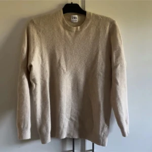 Beige ulltröja från Zara - Säljer en supermysig beige ulltröja från Zara. Perfekt för kyliga dagar med sin mjuka och varma känsla. Tröjan har en klassisk design med rund hals och långa ärmar. Passar både till vardags och lite finare tillfällen. 🧥✨