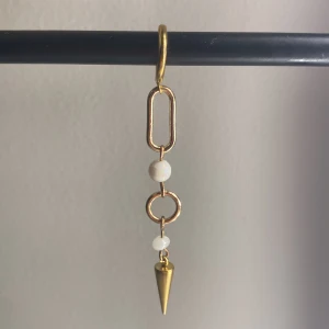 Ett guldigt örhänge med två pärlor - Det är ett guldigt örhänge med pärlor