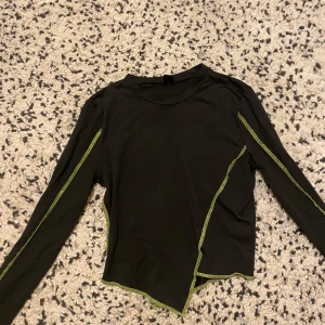 Svart grön topp - Magtröja med asymmetrisk längd, fett cool och snygg känns jätte mjuk och är stretchig.
