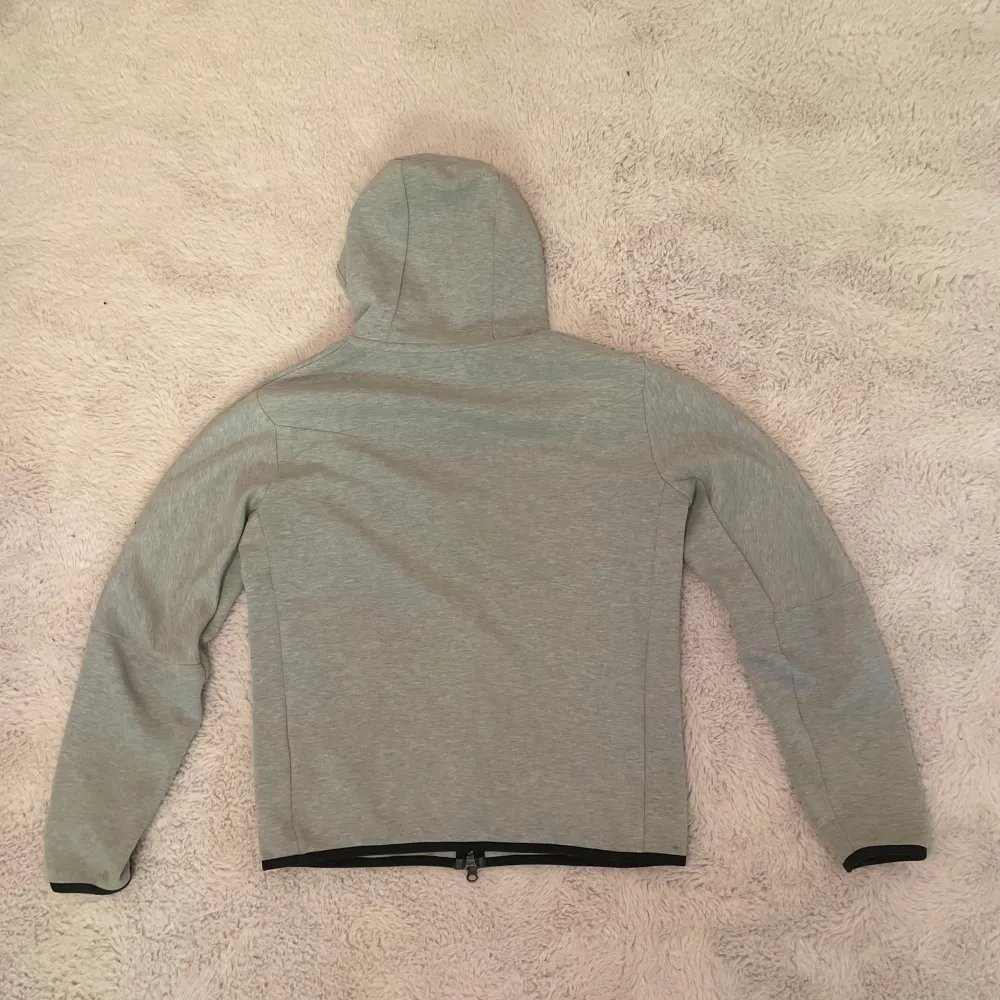 En grå Nike tech fleece storlek S. Den är ganska använd så man ser på bilderna att det är lite slitage men det är inga större fel på den som märks. Självklart äkta, byxor finns o köpa separat tockså.. Hoodies.