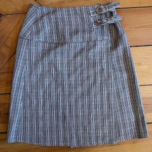 Rutig kjol - Snygg omlottkjol med spännen på sidan. Knälång, ca 57 cm. Passar strl 36-38 Nyskick!