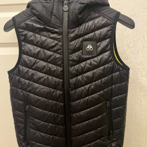 Moose Knuckles Väst - En fin väst som är 10/10 i skick. Endast använt en vår säsong. Den är äkta och köpt i thern lunds, men finns dock inte kvar att köpa längre. Inga skador ele repor!