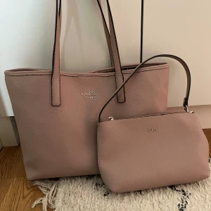 GUESS Vikky Tote 2i1 väska - Väska från Guess, Vikky Tote, rosa i mycket bra skick. En stor väska med tillhörande lite väska. Den lilla väskan går att fästa i den stora eller användas för sig.  Material: läderimitation, tygfoder med leopardmönstrad