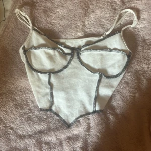 Vit topp - En vit topp med svarta detaljer, ganska kort.