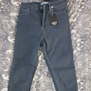 Grå jeans från WXF - Säljer ett par grå jeans från shein i storlek XS. Då de är för korta för mig i benen (jag är 169 cm). De är tillverkade av 96% bomull och 4% elastan, vilket gör dem både bekväma och stretchiga. Perfekta för vardagsbruk med en klassisk design och normal passform. De har en knapp och dragkedja framtill samt fickor både fram och bak.