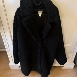 Kappa från HM - Säljer min långa svarta Teddy jacka från HM. Så varmt och snygg!! Storlek L men passar mig som har S. Då sitter den snyggt oversize.