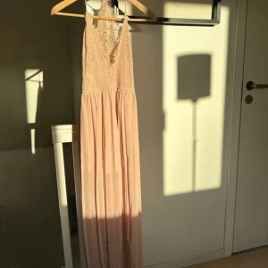 Ljusrosa långklänning från Rare London - Säljer en superfin ljusrosa långklänning från Rare London. Klänningen har en vacker spetsdetalj upptill och är ärmlös med en elegant, flytande kjol. Perfekt för sommarens fester eller en romantisk kväll. Den är i nyskick 